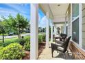 Inviting covered front porch with white columns and charming seating area at 174 Hanks Bluff Dr, Mooresville, NC 28117