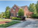 Red brick home with side entry garage, a well-maintained lawn, and mature landscaping at 2301 Keara Way, Charlotte, NC 28270