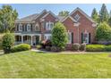 Charming two-story brick home boasts a covered front porch, pristine lawn, and lush landscaping at 2301 Keara Way, Charlotte, NC 28270