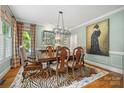 Elegant dining room with stylish chandelier, a zebra rug, and views to the backyard at 2329 Club Rd, Charlotte, NC 28205