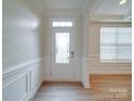 Bright entryway featuring a decorative glass front door, wainscoting, and wood-look flooring at 3022 Burnello Ct, Iron Station, NC 28080