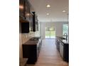 Modern kitchen features stainless steel appliances, dark cabinetry, and granite countertops with exterior door access at 3022 Burnello Ct, Iron Station, NC 28080