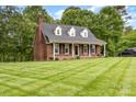 Lovely brick home with manicured lawn, mature trees, and a quaint front porch, offering classic charm and curb appeal at 3049 Stablegate Dr, Gastonia, NC 28052