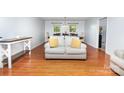 Bright living room featuring hardwood floors, a comfortable sofa, and an open layout to the dining area at 3049 Stablegate Dr, Gastonia, NC 28052
