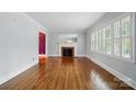 Spacious living room with hardwood floors, fireplace, and large window with plantation shutters at 4220 Castlewood Rd, Charlotte, NC 28209