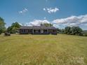 Expansive front lawn of a brick home under a bright sky with fluffy white clouds at 55 Dixie Dr, Taylorsville, NC 28681