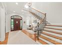 Elegant foyer featuring a wooden staircase, large front door, and stylish furnishings under a skylight at 6831 Conservatory Ln, Charlotte, NC 28210