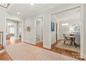 Well-lit hallway showcasing hardwood floors and access to a powder room and dining area, ensuring easy flow at 6831 Conservatory Ln, Charlotte, NC 28210