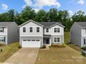 Inviting two-story home featuring a well-maintained lawn, a two-car garage, and classic architectural details at 703 Pointe Andrews Dr, Concord, NC 28025