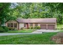 Charming single-story home with a well-manicured lawn, a two-car garage, and beautiful mature trees at 14027 Springwater Dr, Matthews, NC 28105