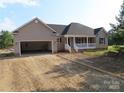 Charming single-Gathering home featuring a covered front porch and an attached two-car garage with gravel driveway at 153 Mason Tanner Ct, Rock Hill, SC 29730