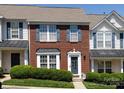 Charming red brick townhome featuring blue shutters, manicured bushes, and a welcoming front door at 2147 Lake Breeze Ln, Denver, NC 28037