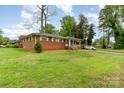Single-story brick home with a covered porch and carport, surrounded by a lush green lawn and mature trees at 2885 Wright Ave, Salisbury, NC 28147