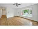 Sunlit living room with hardwood floors, large bay window, and neutral paint scheme at 7412 Woodstream Dr, Charlotte, NC 28210
