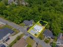 An aerial view of a home highlighting property lines in a residential neighborhood surrounded by lush trees at 83 Woodsdale Se Pl, Concord, NC 28025