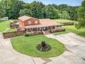Expansive aerial view of brick home, fenced yard, and inviting outdoor spaces. Mature trees in background at 907 Sikes Mill Rd, Monroe, NC 28110