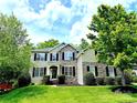 Charming two-story home with lush green lawn, stone accents and black shutters provides great curb appeal at 10008 King George Ln, Waxhaw, NC 28173