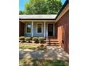 Inviting front entrance with brick steps, gray siding, white columns, and well-maintained landscaping at 13416 Four Oaks Ln, Matthews, NC 28105