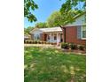 Quaint brick home featuring traditional architecture with shuttered windows and manicured front yard at 13416 Four Oaks Ln, Matthews, NC 28105