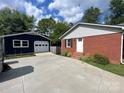 View of a brick home and a detached blue garage with a concrete driveway at 15333 Catawba S Cir, Matthews, NC 28104