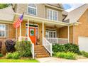 Inviting front porch featuring brick steps, white railings, and a vibrant orange front door with wreath at 1655 Essex Hall Dr, Rock Hill, SC 29730