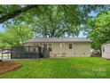 Home backyard with a deck, a lush lawn, mature trees, and a storage building at 1700 Emerywood Dr, Charlotte, NC 28210
