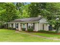 Classic ranch home with a brick facade, a walkway, black shutters, and lovely green landscaping at 1700 Emerywood Dr, Charlotte, NC 28210