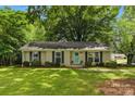 Charming brick ranch home with a manicured lawn, black shutters, and a vibrant teal front door at 1700 Emerywood Dr, Charlotte, NC 28210