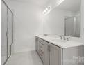 Bright bathroom featuring a double vanity, stone counters, modern fixtures, and a glass-enclosed shower at 2134 Barrowcliffe Nw Dr # 0006, Concord, NC 28027
