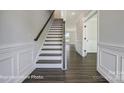 Welcoming foyer with hardwood floors, a staircase with dark handrail, and decorative trim at 6027 Veld Ct # 82, Charlotte, NC 28215