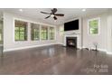 Spacious living room with hardwood floors, a ceiling fan, a fireplace, and three large windows overlooking the yard at 15536 Oleander Dr # L228, Charlotte, NC 28278