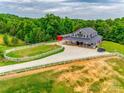 An aerial view of a stunning horse property featuring a barn-style house, green pastures, and white fences at 3091 Old Meeting House Rd, Sharon, SC 29742