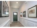 Elegant hallway featuring beautiful white wainscoting, fresh paint, and a view of the home's entrance at 4245 Millstream Rd, Denver, NC 28037