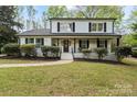 Charming two-story home with a covered front porch, landscaped yard, and fresh white and black paint at 5910 Grosner Pl, Charlotte, NC 28211