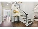 Bright foyer with hardwood floors, white staircase with black accents, and elegant decor at 7812 Seton House Ln, Charlotte, NC 28277