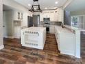 Newly renovated kitchen features white cabinets, an island with bar seating, and stainless steel appliances at 10406 Baskerville Ave, Charlotte, NC 28269