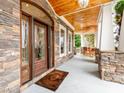 Inviting front porch with stone accents, a wood ceiling, and a stylish wooden front door at 123 Yellow Jacket Cir, Mooresville, NC 28117