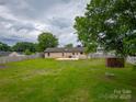 Expansive backyard with a wooden fence, mature tree, and a concrete patio area, ideal for outdoor enjoyment at 133 Pheasant Run Rd, Troutman, NC 28166