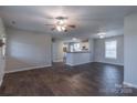 Open living area with hardwood floors, a ceiling fan, and a breakfast bar connecting to the kitchen at 133 Pheasant Run Rd, Troutman, NC 28166