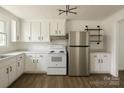 Bright kitchen features white cabinets, new stainless steel appliances, stylish lighting, and wood-look flooring at 1401 Woodman Hall St, Shelby, NC 28152