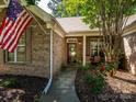 Inviting front porch of a brick home with an American flag, flowers, and seating area at 14336 Northridge Dr, Charlotte, NC 28269