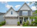 Beautiful home with gray siding, stone accents, covered entry, and a two-car garage under a blue sky at 145 Yellow Birch Loop, Mooresville, NC 28117