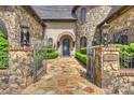 Grand entrance to stone home with iron gate, paved walkway and ornate wrought iron door at 16909 Jetton Rd, Cornelius, NC 28031