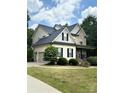 Charming two-story home featuring a manicured lawn, stone accents, a side-entry garage, and a welcoming covered porch at 3320 Harvey Ln, Monroe, NC 28110