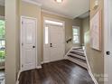 Bright foyer featuring hardwood floors, staircase, and a stylish white door with transom window at 4315 Poplar Grove Dr, Charlotte, NC 28269