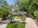 Picturesque lakefront home featuring mature landscaping, a circular driveway, and a stone facade at 570 Blue Heron Rd, Salisbury, NC 28146
