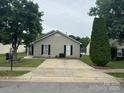 A charming single-story home featuring a concrete driveway and neutral siding with black shutters at 5804 Fairchase Ave, Charlotte, NC 28269