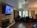 Living room featuring a wood-paneled wall with a fireplace, a crystal chandelier, and a large window for natural light at 703 S Highway 27 Hwy, Stanley, NC 28164