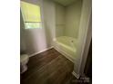 Cozy bathroom with a garden tub, wood-look floors, and a neutral color palette at 716 Coy Ct, Charlotte, NC 28216