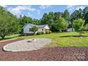 Charming home featuring a front yard fire pit, lush green lawn and mature trees at 120 Mossy Rock Trl, Iron Station, NC 28080